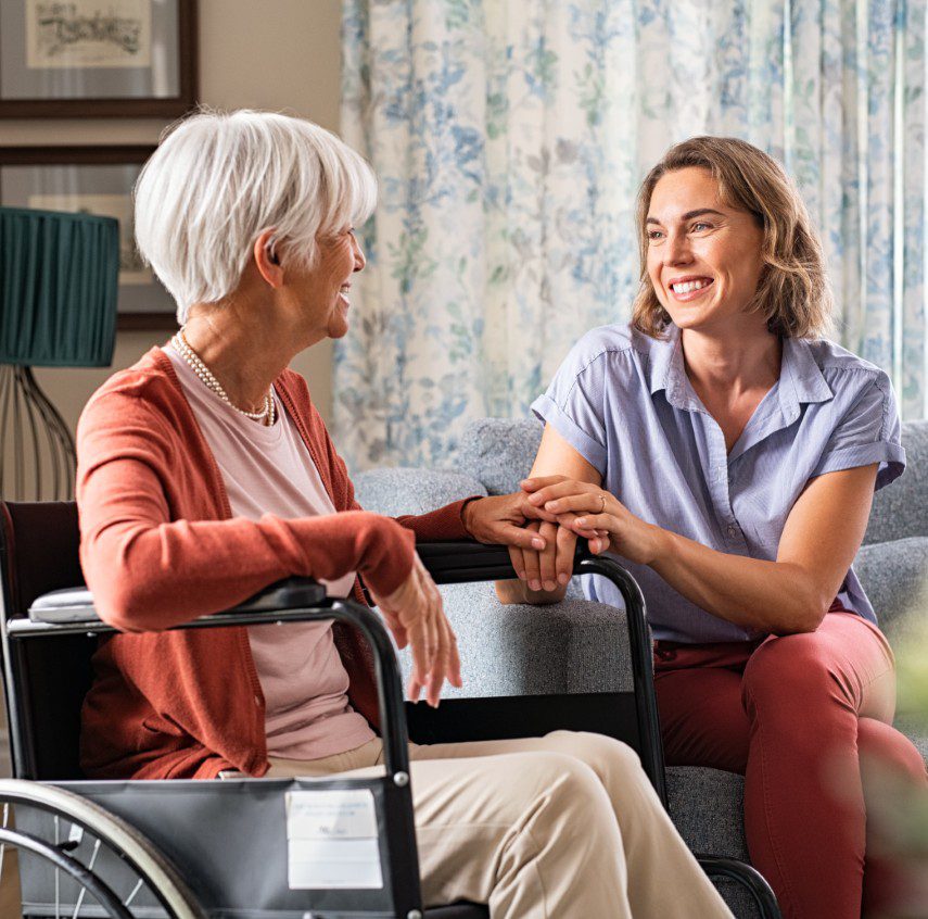 GettyImages-1316202210 Woman smiling, holding elderly woman's hand.