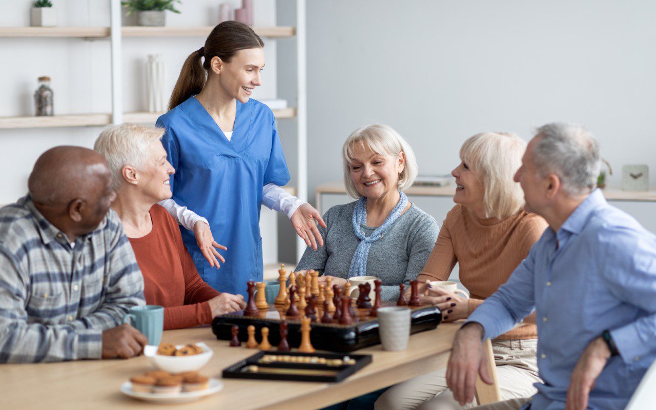 GettyImages-1479214725 Group playing chess and talking at table.