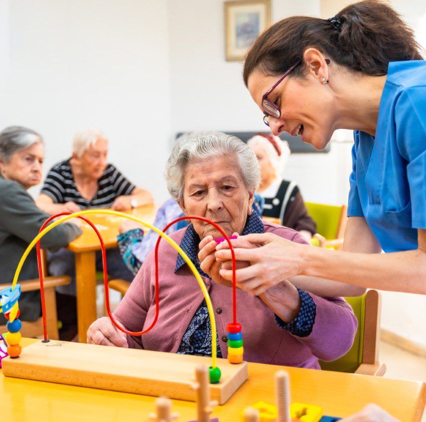 GettyImages-2180586838 Elderly woman engaged in activity with caregiver.