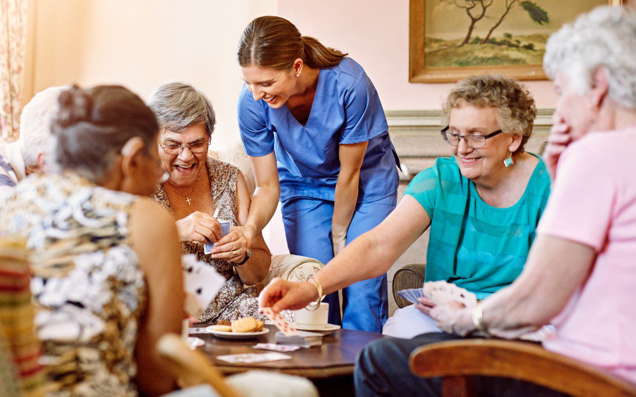 GettyImages-516847324 Seniors and caregiver playing cards together.