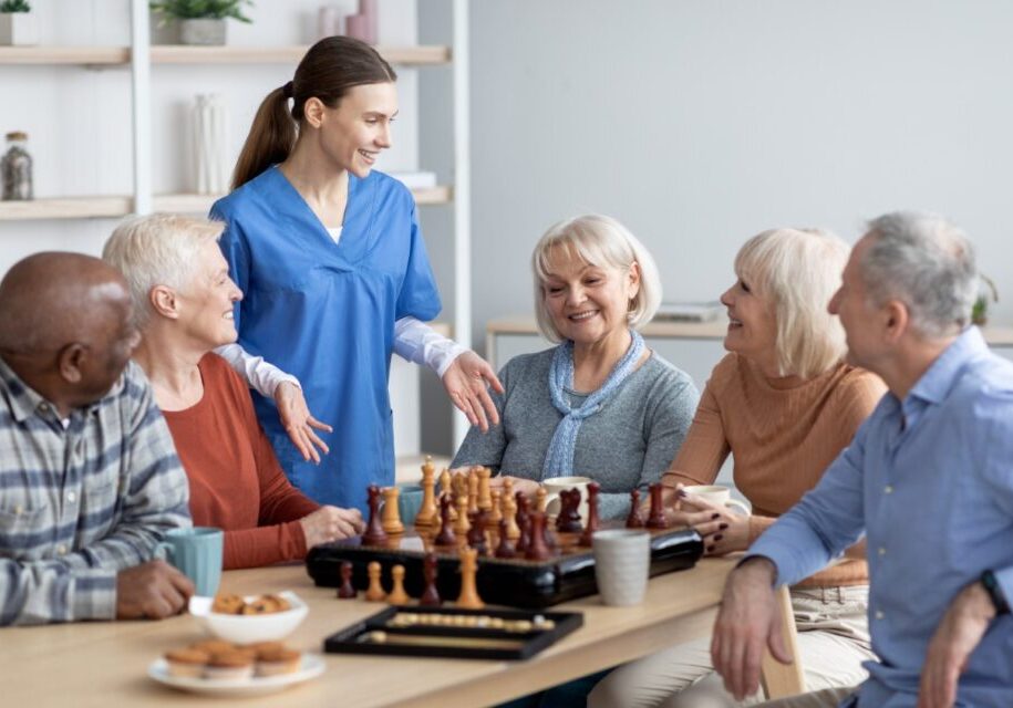 Group playing chess and talking at table.