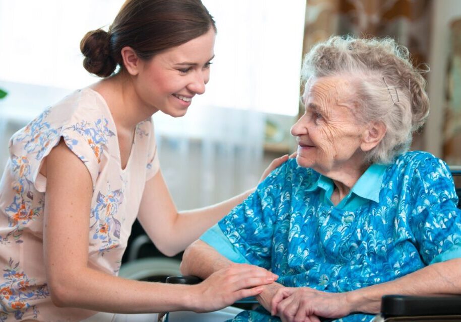 Young woman comforting elderly woman in wheelchair.