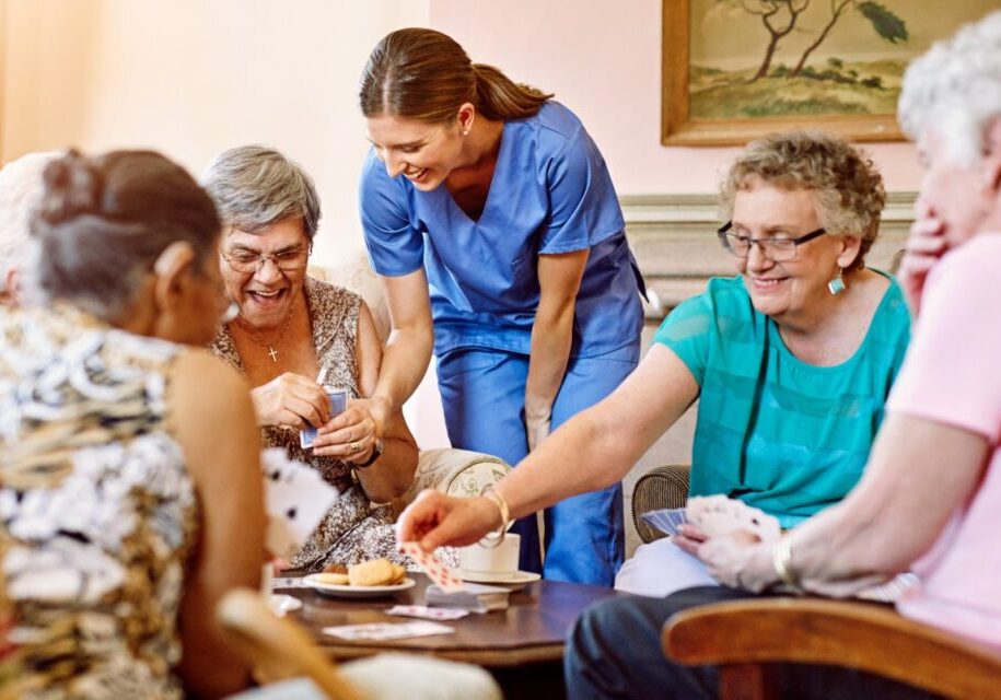 Seniors and caregiver playing cards together.